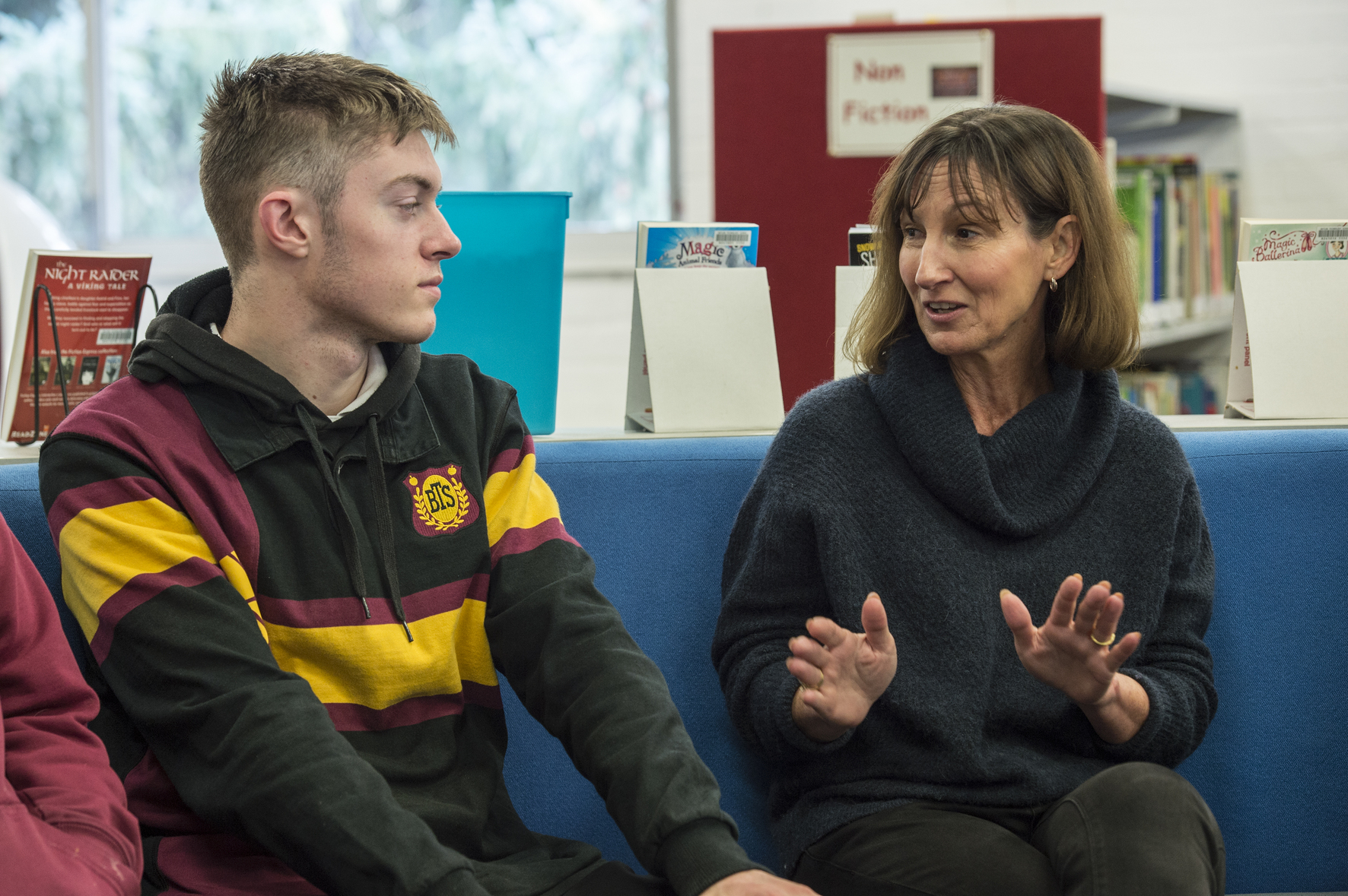 A student speaking with an adult in a library