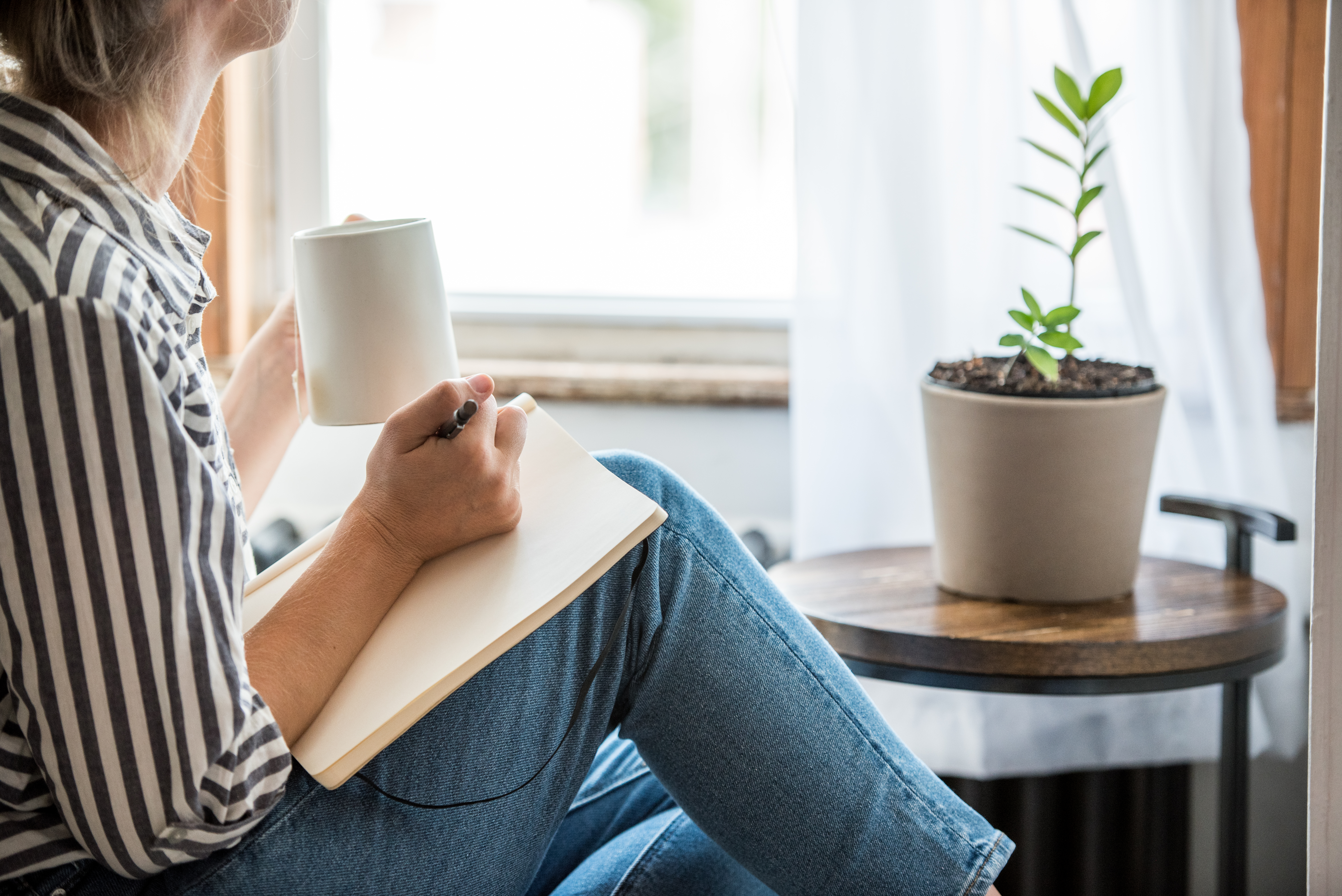 An adult journalling while drinking tea